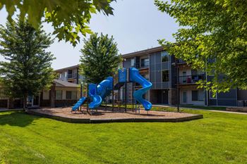 A blue slide in a playground in front of a building.